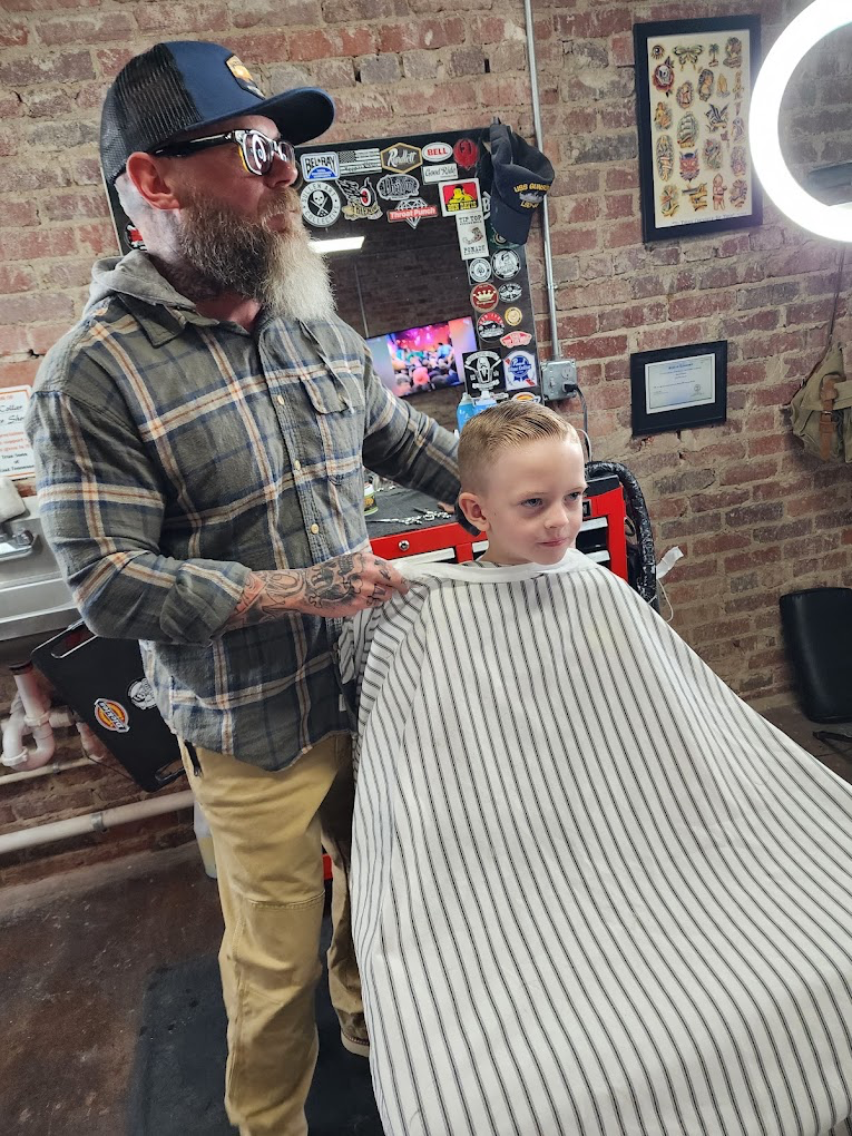 Barber with a young client in the Blue Collar Barber Shop chair